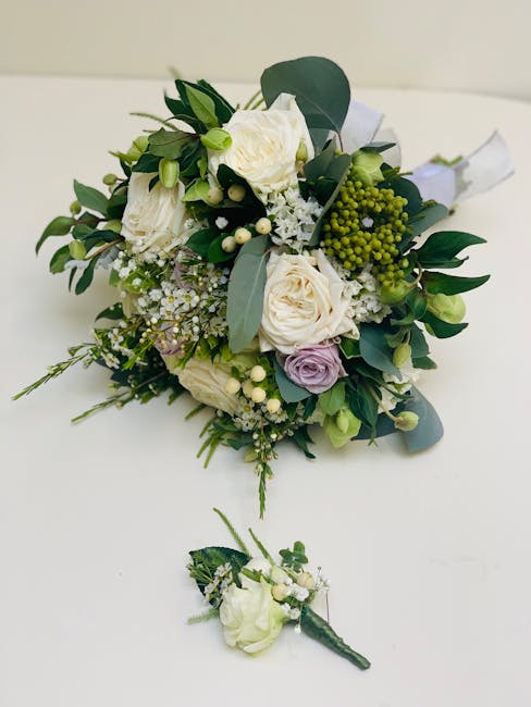 A bouquet featuring a harmonious arrangement of cream, white, and pale lavender roses, complemented by sprigs of white baby’s breath, small green berries, and lush eucalyptus leaves. The flowers are